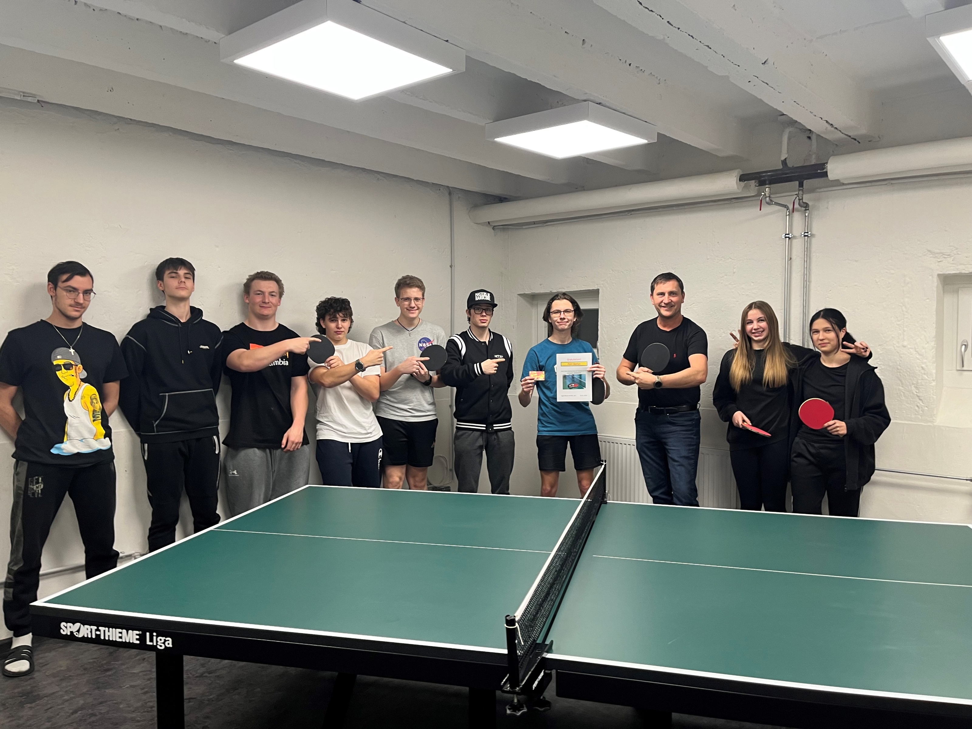 Gruppenbild von den Schüler*innen und Herrn Dietrich hinter dem Tischtennistisch